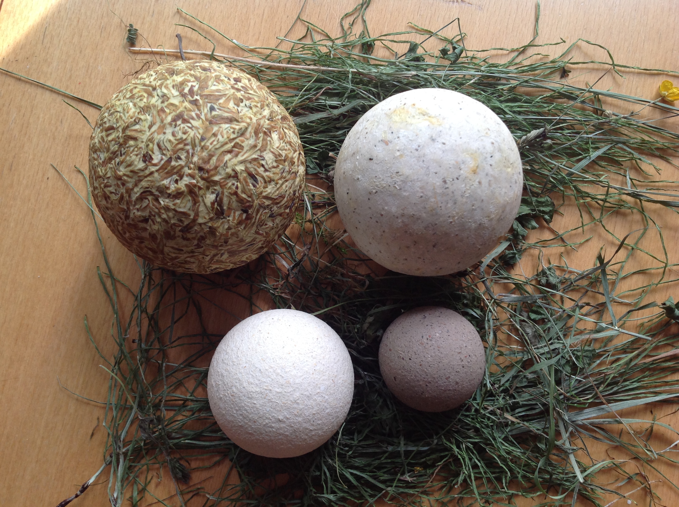 Ceramic globes of different sizes and colors, displayed on top of some dried grasses